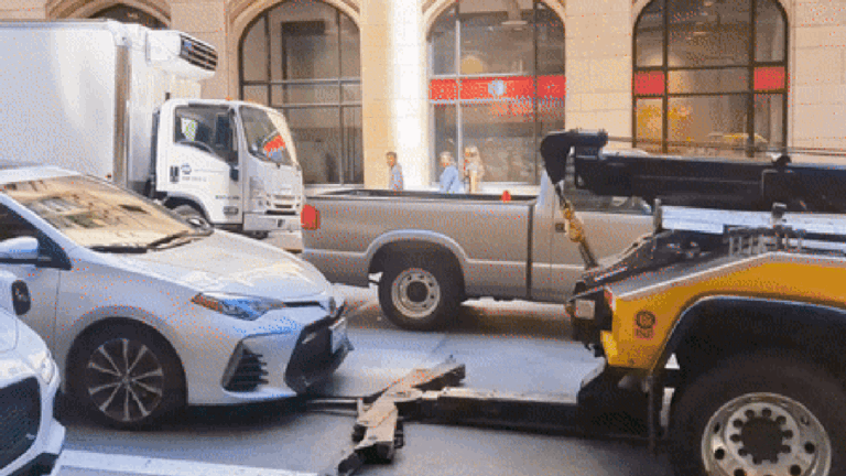 Tow truck tries to pick up occupied car in the middle of heavy traffic